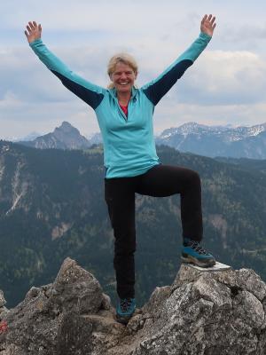Sportlich-dynamische blone Frau auf einem Berggipfel