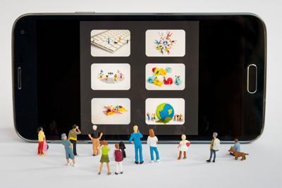Verschiedene Miniaturmännchen stehen vor dem Display eines Smartphones