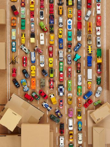 Viele bunte Spielzeugautos auf einer Pappautobahn im Stau