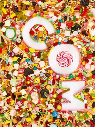 Jede Menge bunte Bonbons und Süßigkeiten mit den Buchstaben c o m in der Mitte