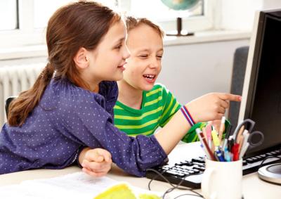 Mädchen und Junge schauen auf einen Computermonitor 