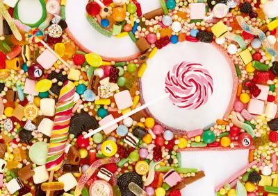 Jede Menge bunte Bonbons und Süßigkeiten mit den Buchstaben c o m in der Mitte