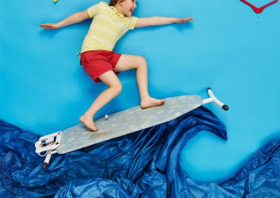 Surfen macht Spaß! Ein kind surft fröhlich auf Papierwellen und Bügelbrett